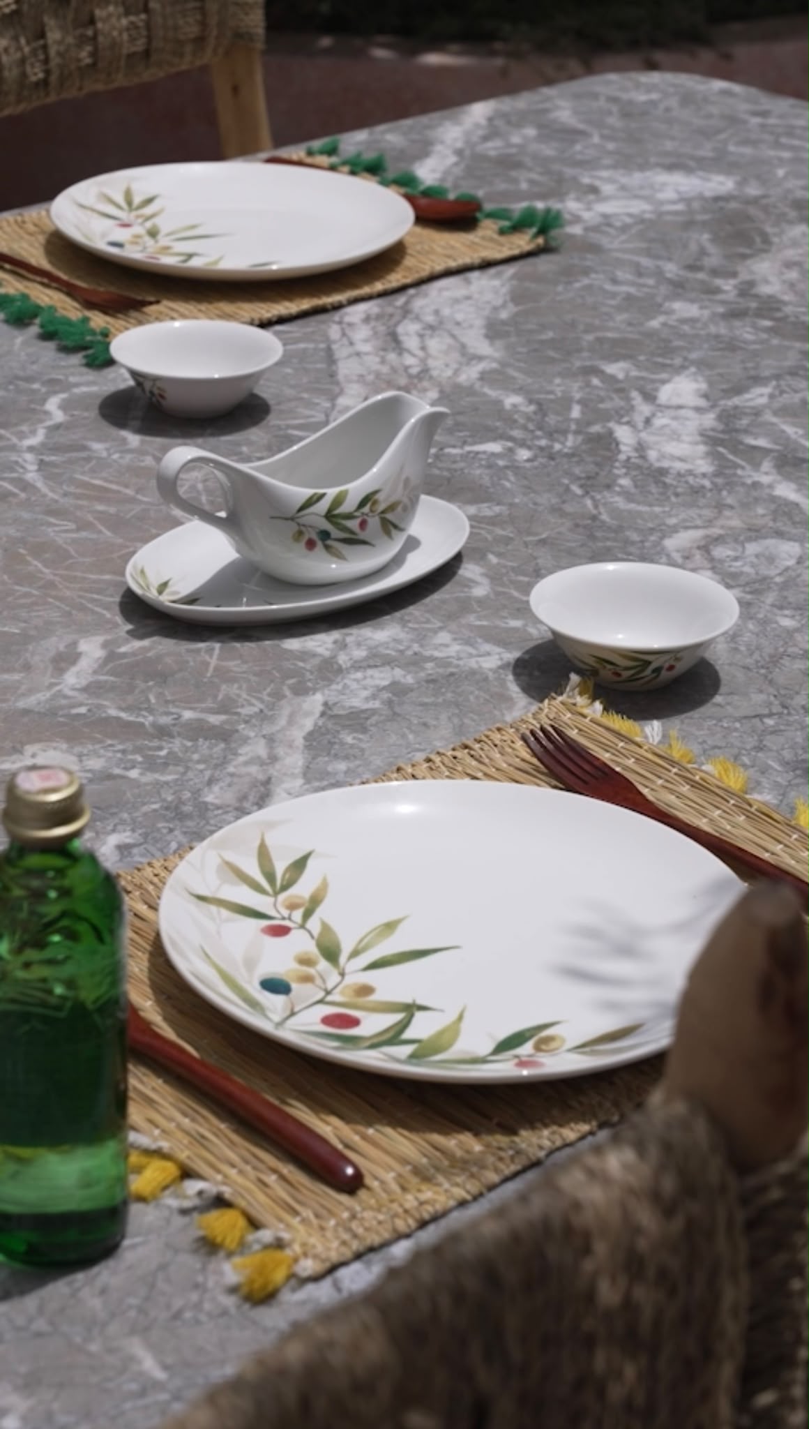 Hand-painted olive tableware and woven placemats at Dar Cherfa