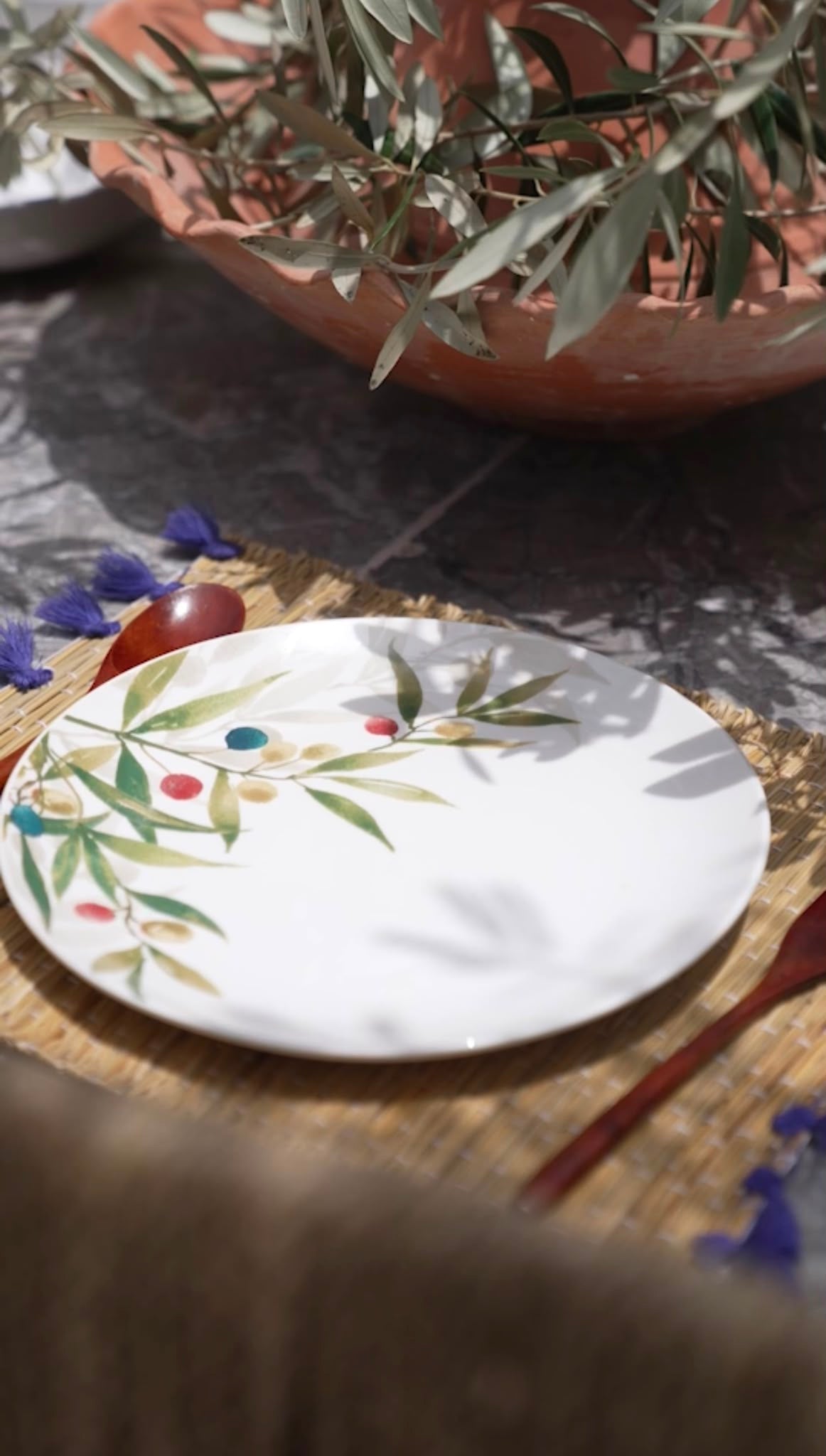 Olive-patterned plate beneath olive branches at Dar Cherfa