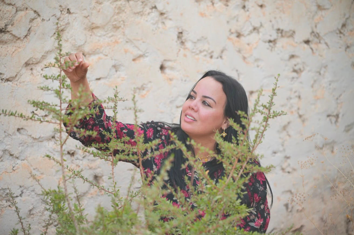Lalla Meriam discovering aromatic plants beside a stone wall in Morocco
