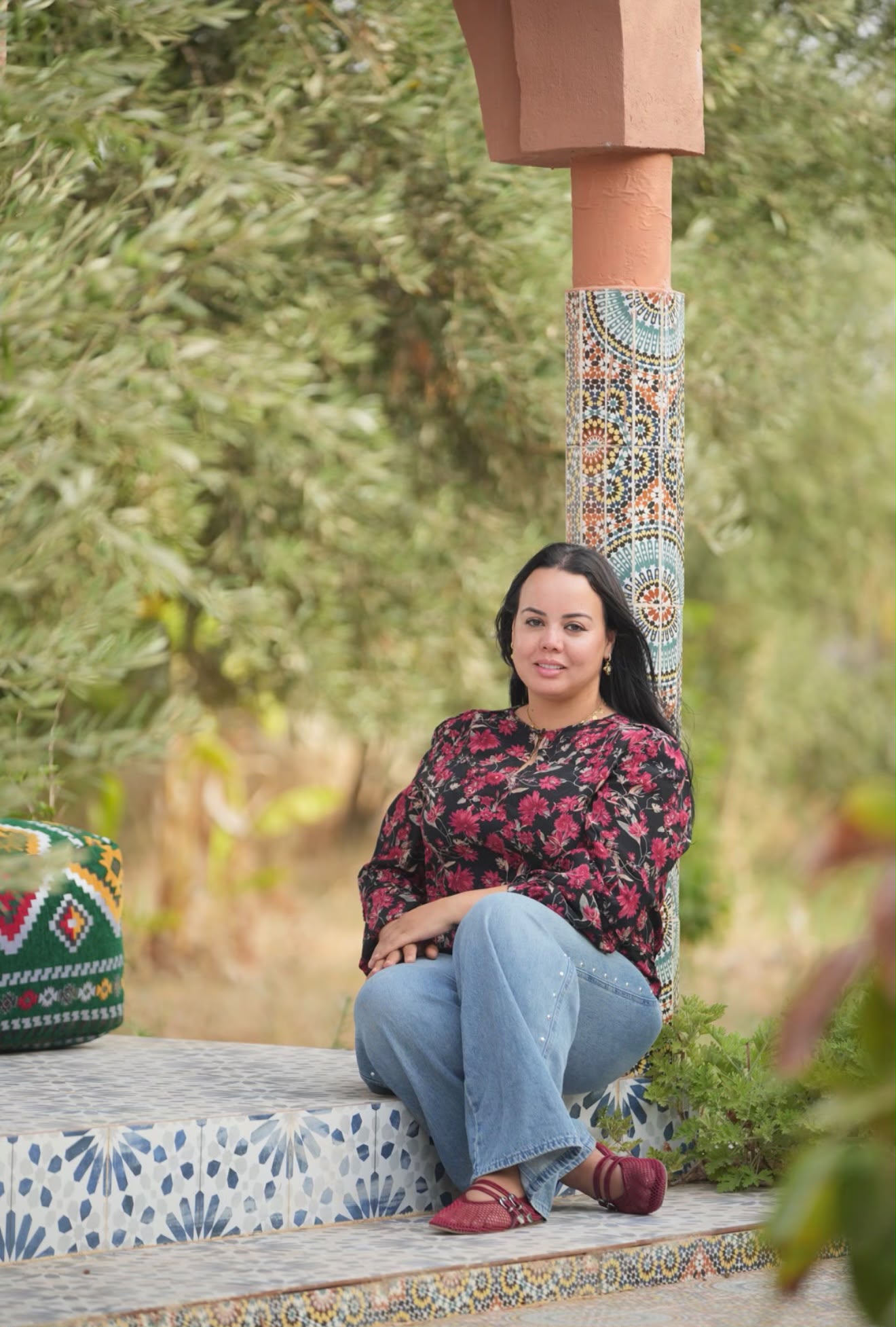 Lalla Meriam seated among olive trees and Moroccan mosaic at Dar Cherfa